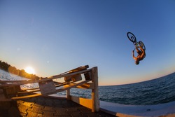 Man jumps a bicycle into the water from a pier