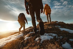 Small group of tourists walks at mountain top at sunset time. Close up photo