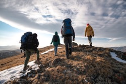 Group of diverse tourists or hikers walks on mountain top