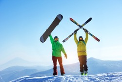 Skier and snowboarder stands mountain top with ski and snowboard in hands. Skiing and snowboarding concept. Sheregesh ski resort