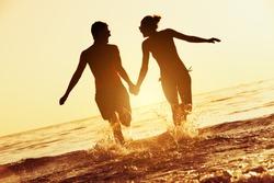 Happy couple runs to sunset sea. Silhouette tropical vacations concept