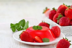 Fruit jelly with fresh strawberry. Healthy food. Strawberry jelly on white plate. Summer dessert with fruit jelly and fresh strawberry.