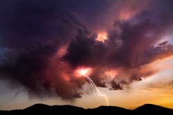Lighting bolt striking from colorful clouds at sunset in the Nevada desert