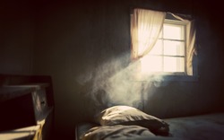 Vintage treated old abandoned bedroom with smoke lit by an open window with curtains