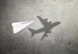 Paper plane in mid flight with shadow of a real plane