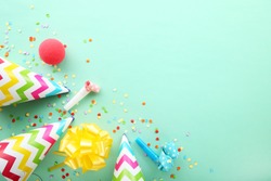 Birthday party caps, blowers and confetti on mint background
