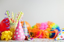 Birthday party caps, blowers and orange glasses on grey background