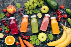 Smoothie in plastic bottles with fruits and vegetables on wooden background
