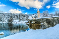 Church of Sv. John the Baptist and a bridge by the Bohinj lake  in winter, Slovenia 