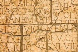 Cracked wall with Latin inscriptions and Roman letters, marble background. 