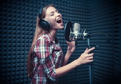 Young woman singing in a recording studio