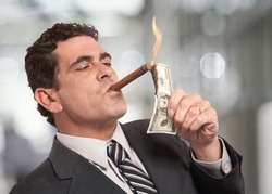 Rich businessman lighting cigar with $100 dollar bill