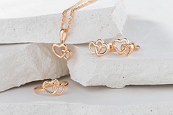 Jewellery set of hearts shape rose gold ring, pendant necklace and stud earrings on white background. Romantic  jewelry. Advertising still life product concept for Valentines Day