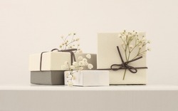 Craft gift boxes with flower on light beige wall copy space background. Minimalism style template background.