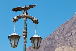 Old public lamp post with sacred inca animals sculpture in central ollaytantambo square in Peru,