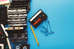 Retro audio cassettes and pencil on blue background. Top view on vintage tapes and simple device for rewinding, copy space. Obsolete technology concept
