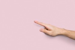 Male hand pointing up on virtual object with index finger isolated on pastel pink background, closeup, cutout, copy space