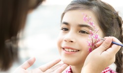 Children face painting. Little girl having fun, making creative floral design outdoors, copy space