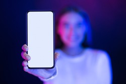 Girl showing blank smartphone screen over neon studio background, blue and pink lights