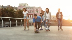 Active Teenagers. Diverse Teen Friends Riding on Skateboards and Rollers, Having Fun Together On Summer Evening, panorama, empty space