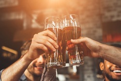 Men Drinking Draft Beer And Clinking Glasses At Pub, Closeup