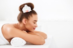Beautiful girl relaxing at light spa salon with closed eyes, side view, free space