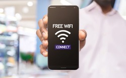 African american man demonstrating smartphone connected to free wifi hotspot in shopping center, selective focus on device