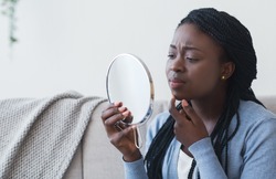 Problem Skin Concept. Black Woman Looking In Round Mirror and Touching Her Face, Worry About Pimple, Closeup