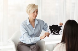 Professional Psychologist Testing Female Patient Showing Inkblot Picture Sitting In Office. Selective Focus