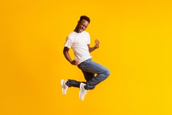 Successful moment. Happy excited young black man jumping over yellow background, copy space