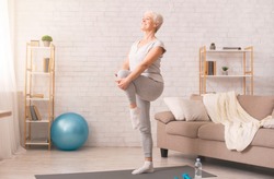 Gym at home. Active senior woman doing legs exercise at home, empty space