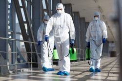 People in virus protective suits and mask disinfecting buildings of coronavirus with the sprayer,