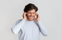 Ear pain concept. Man grimaces and touches ears, free space