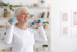 Healthy Lifestyle. Smiling Senior Lady Exercising With Dumbbells At Home, Free Space