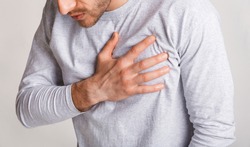 Stress and health concept. Young man experiences chest pain and leans, close up, panorama, cropped