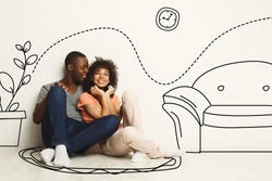 Black guy and his girlfriend imagining their new furnished home against white wall with interior drawings