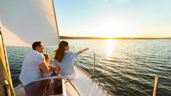 Family Of Three Sailing On Yacht Sitting On Sailboat Deck Looking At Sunset At Seaside. Dream Vacation Concept. Free Space