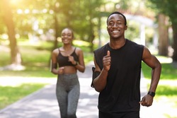 Active African American Couple Jogging In Summer Park, Enjoying Healthy Lifestyle And Training Outdoors, Selective Focus With Copy Space