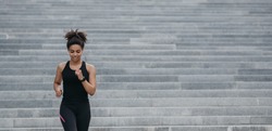 Motivated african american girl in sportswear with fitness tracker doing cardio workout outdoors, free space