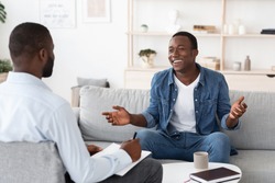 Successful Therapy. Cheerful black man talking to psychologist on meeting at his office, sharing his progress with doctor