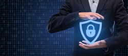 Internet Privacy, Technology And Data Protection Concept. Closeup of businessman holding virtual security shield hologram with padlock. Panorama, banner with binary code in the background
