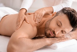 Sports massage. Massage therapist massaging shoulders of a male athlete,  working with Trapezius muscle. Toned image. Masseur doing massage on man  body in the spa salon. Beauty treatment concept. Stock Photo