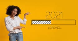 Waiting For 2021 New Year. Joyful Black Woman Pointing Finger At 2021 Loading Process Bar Standing Over Yellow Background. Anticipation, Awaiting Upcoming Better Year Concept. Panorama