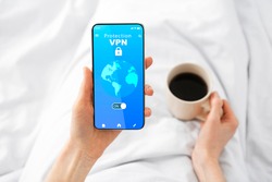 VPN Virtual Private Network App Opened On Mobile Phone In Female Hands, Point Of View Of Unrecognizable Woman Using Modern Application For Cyber Security And Information Privacy, Drinking Coffee
