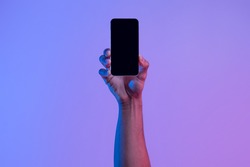 Social network and modern technology. Female hand holds phone with blank screen on neon background, close up, copy space