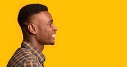 Profile Shot Of Cheerful Young African American Guy Looking Aside At Copy Space, Side View Of Positive Black Millennial Man In Checkered Shirt Standing Isolated On Yellow Background, Panorama