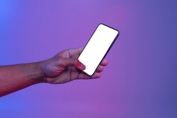 Black Male Hand Holding Smartphone With Glowing White Screen Under Neon Light Over Purple Background, Unrecognizable African American Man Showing Free Copy Space For Your App Design, Mockup Image