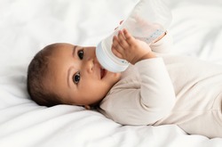 Cute little African American baby drinking from bottle