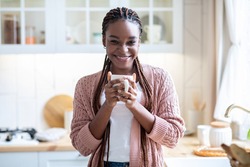 Home Relax. Portrait Of Happy African American Female Drinking Morning Coffee In Kitchen, Cheerful Black Woman Holding Cup With Hot Drink And Smiling At Camera, Enjoying Domestic Rest, Free Space