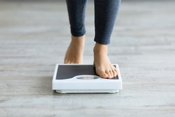 Unrecognizable young Indian woman stepping on scales to measure her weight at home, closeup of feet. Cropped view of millennial lady checking result of her slimming diet. Healthy living concept